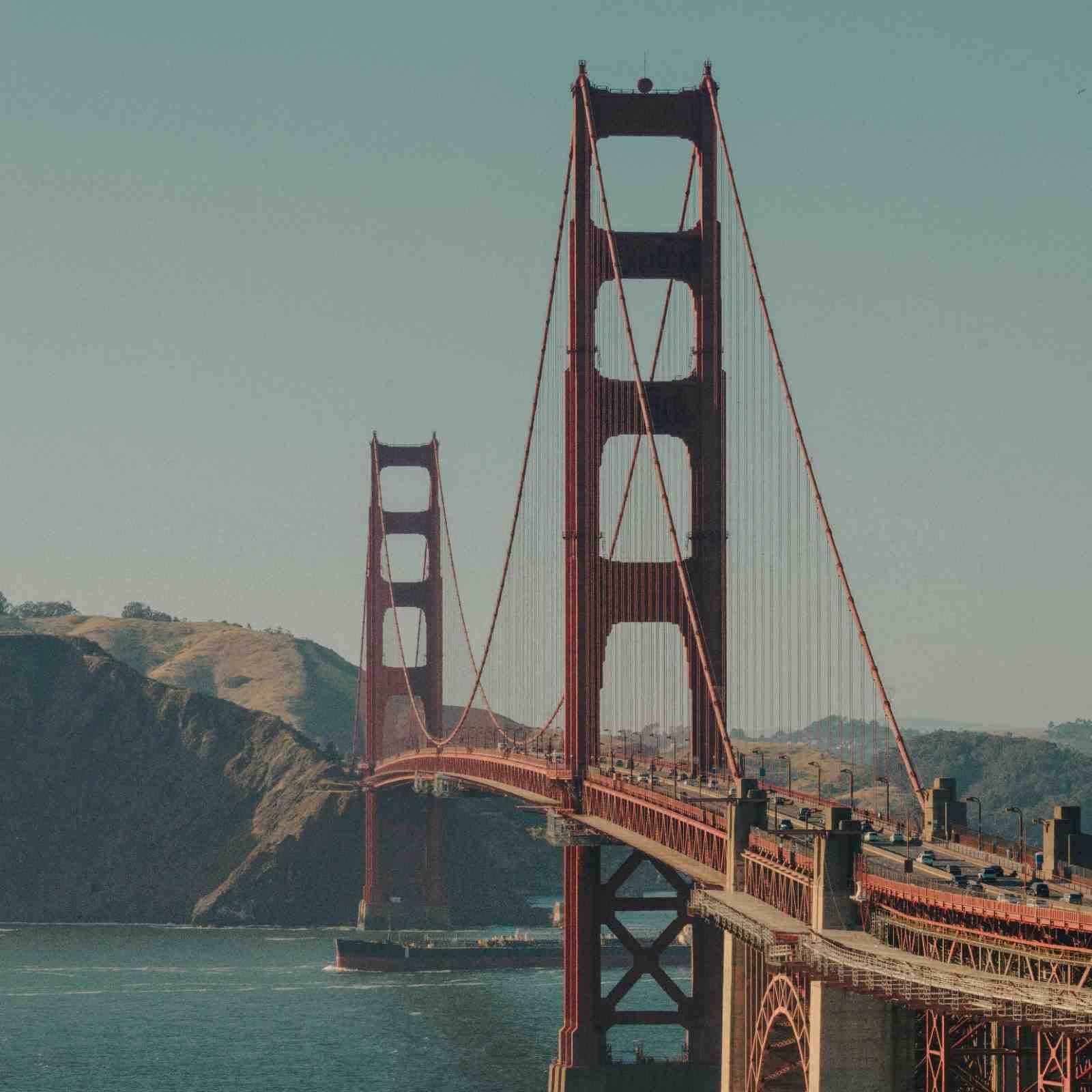 Suspension bridge spanning open water — demand staying connected across each layer of the stack.